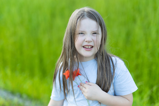 Only One Young Girl with Poppies. Grass in Background. Poland.