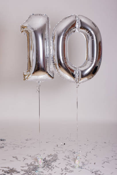Foil number 10 air balloons and confetti over white background birthday party concept - foil number 10 air balloons and confetti over white background 10 balloon stock pictures, royalty-free photos & images