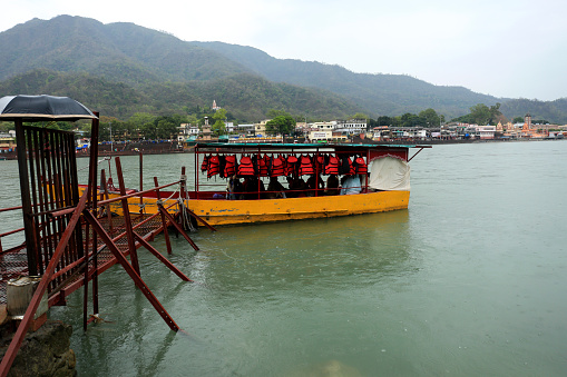 Motorboat crossing holy river Ganges in Uttarakhand, India during rainy season.