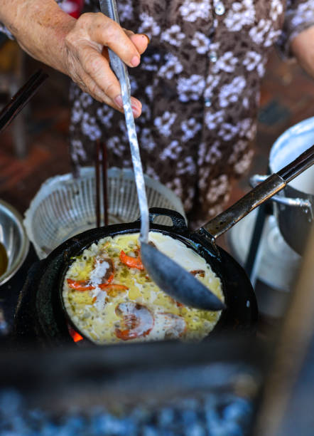 An old woman cooking traditional seafood pancake at old kitchen in Nha Trang, Vietnam.