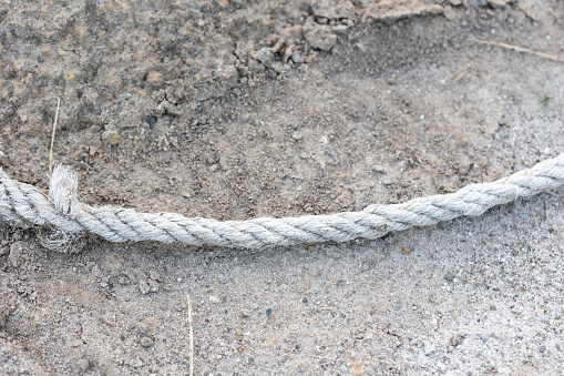 Coiled climbing rope and steel carabiner. Mountain climbing equipment: harness, brakes, quickdraws, self-insurance, belay device eight. On a stone background with cracks. Flatlay, copy space