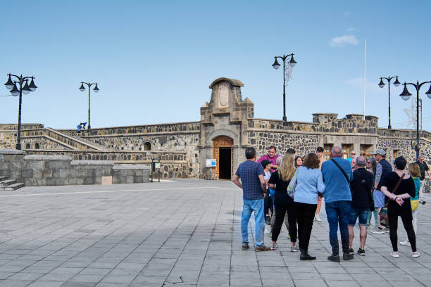 grupa turystów przed murem castillo de sant felipe na plaza de europa w puerto de la cruz, teneryfa, wyspy kanaryjskie. - standing mature women professor light zdjęcia i obrazy z banku zdjęć