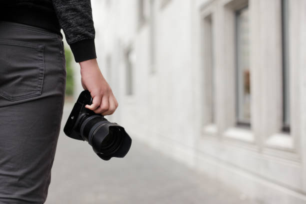 istock modern dslr camera in male hands, copy space over concrete building background 1513855228