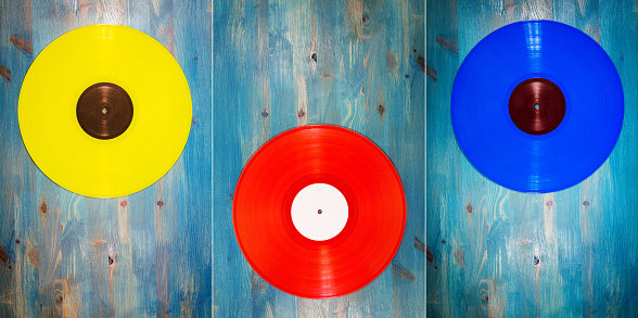 Collection of images with different color vinyl records on blue wooden background