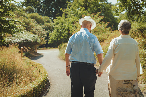 Rear view of a senior couple going for a relaxing walk in the park holding hands