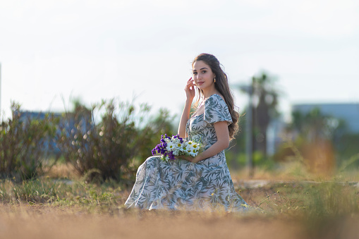 Beautiful woman in the meadow with a bouquet of flowers.