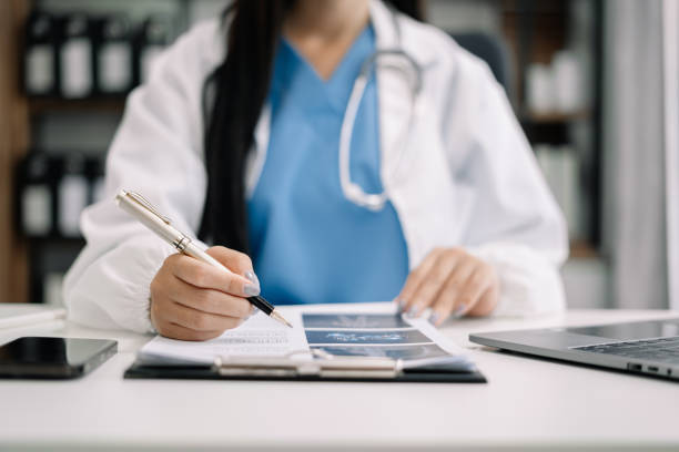 istock Female medicine doctor, physician or practitioner in lab room writing on blank notebook and work on laptop computer with medical stethoscope on the desk at hospital. Medic tech concept. 1513876720