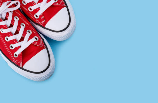 istock Red sneakers on blue background with copy space. Youth shoes. 1513881615