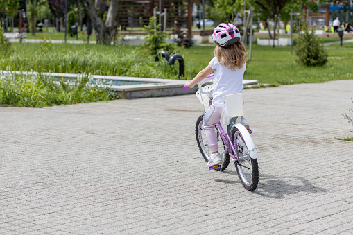 Girl with protective helmet riding a bicycle, rear-view