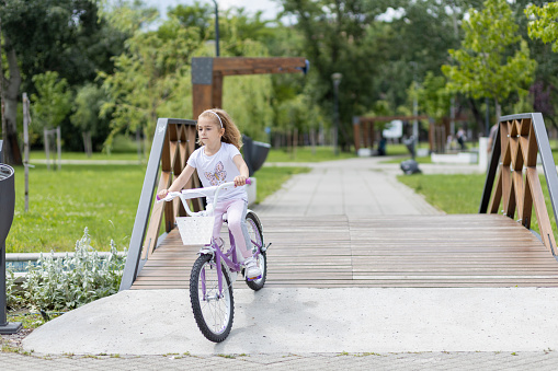 Child riding bike over a wooden bridge