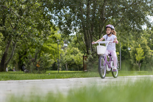 Child riding a bicycle all by herself in a park
