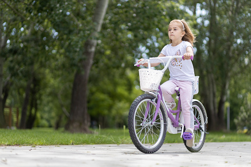 Child riding a bicycle all by herself in a park