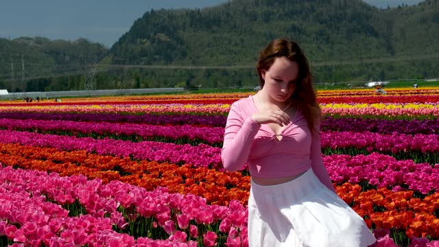 collection of videos and photos where a girl in a white skirt walks through field with tulips blue background sky mountains bright flowering fields teenager young woman walk outdoors beauty self-care