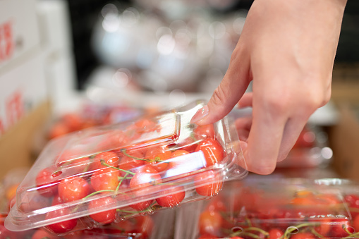 Woman's hand buying packed cherries