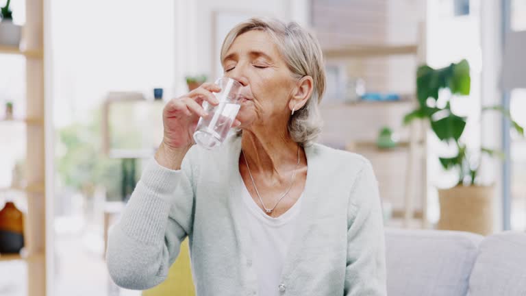 Wellness, home or healthy old woman drinking water for healthcare or natural vitamins in a house. Retirement, elderly relaxing or thirsty senior person refreshing with liquid for energy or hydration