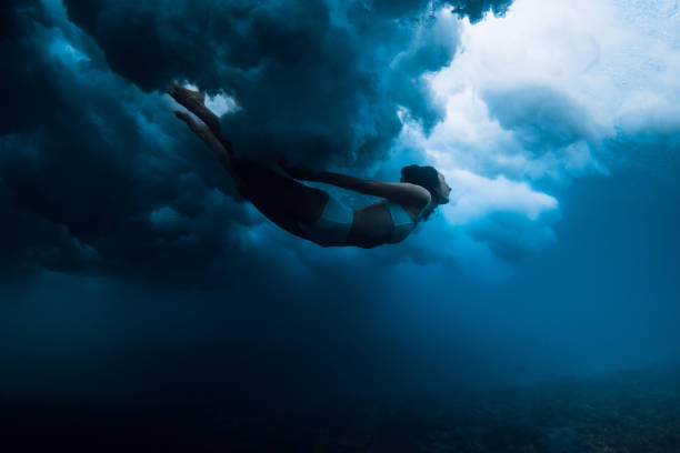 istock Woman under powerful wave with foam in blue ocean. Duck dive without surfboard 1513971024