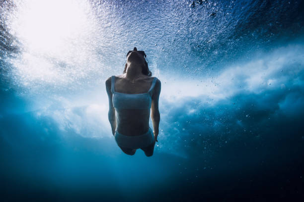 istock Woman in bikini dive without surfboard underwater with ocean wave. Lady duck dive under barrel wave 1513977135