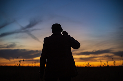 Silhouette of a businessman at sunrise in nature. The concept of business, negotiations, development, success, startups, new opportunities.