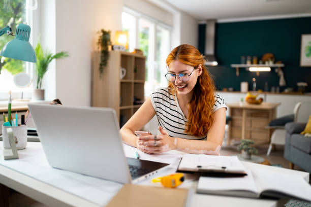 istock Redhead woman with vitiligo and acne on her face, using mobile phone while working from home 1514012740