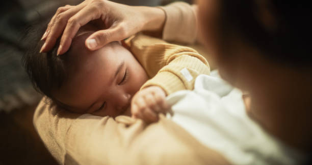 ritratto ad angolo alto di un simpatico bambino asiatico che si nutre dal seno di sua madre. momento intimo tra neomamma e neonato che mostra amore materno, tenerezza e affetto incondizionato. - human pregnancy toddler child mother foto e immagini stock