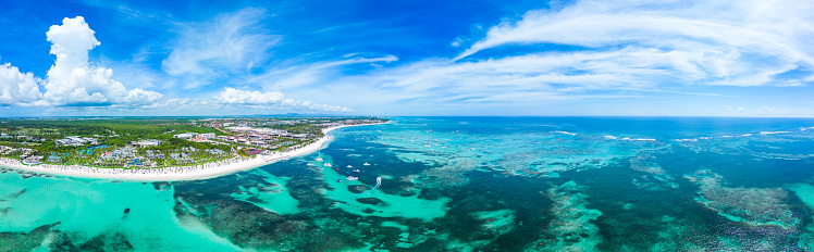 Aerial panorama of the large tropical beach with white sand and turquoise water of the Caribbean Sea. Top places for summer vacations in all Inclusive resorts and hotels in Punta Cana. High quality photo