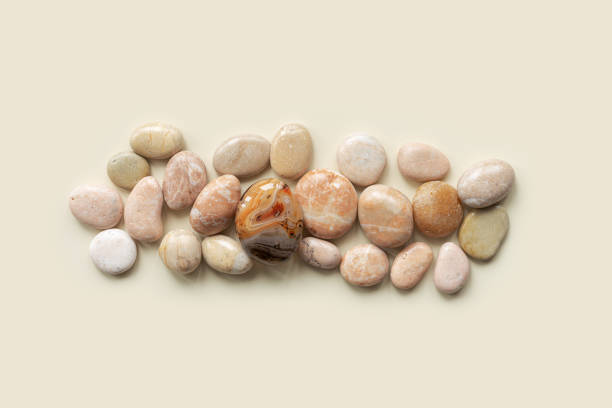 審美的な最小限のフラットは、コピースペースのあるベージュの背景に海の小石で横たわっていました。天然の滑らかな石のパステルカラーとサルドニクスの宝石からの行。夏のコンセプト�