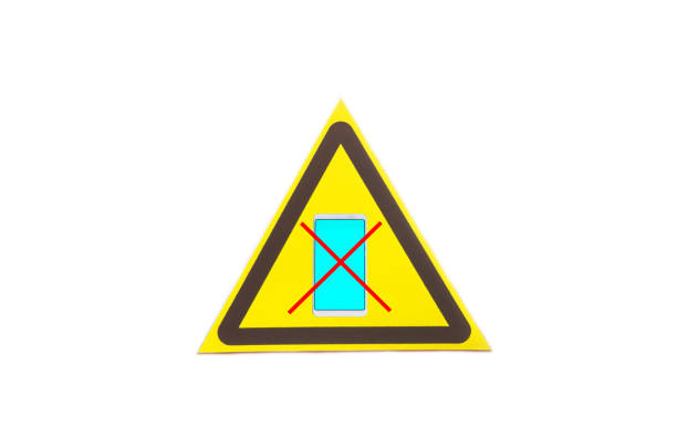Warning sign crossed out smartphone in a yellow triangle on a light background close-up