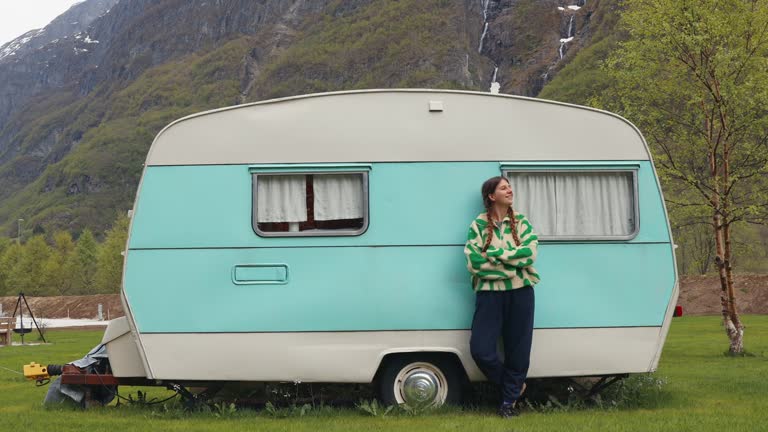 Happy Female Staying by Camper Trailer with View of Mountains and Waterfall in Norway