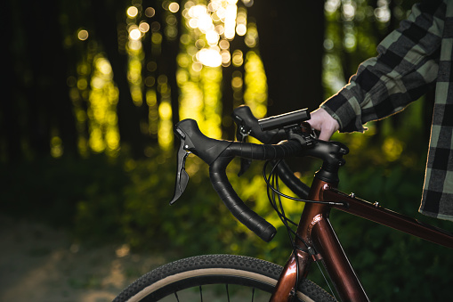 A man with a bicycle in the forest at sunset, the concept of outdoor activity, travel and sports.