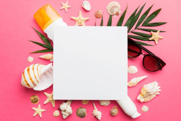 istock Summer time concept with blank greeting card and blank white paper on colored background. Seashells from ocean shore in the shape of frame separated with space for text top view 1514133550