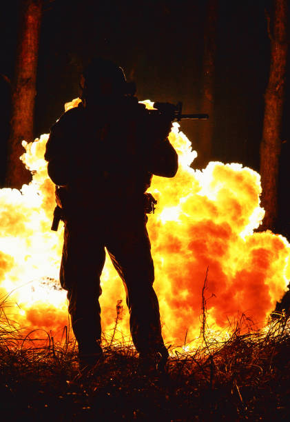 istock Backlit silhouette of special forces marine operator in forest on fire explosion background. Battle, bombs exploding, they fighting no matter what 1514178794