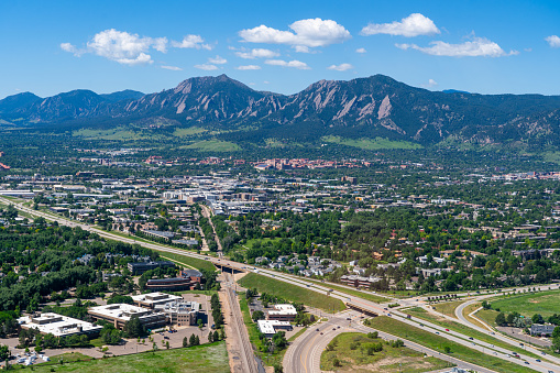 Aerial photo above Boulder Colorado on a clear day looking southwest towards University of Colorado and Flatiron Mountains and the city of Boulder with Highway 157 (Foothills Parkway) cutting across the foreground