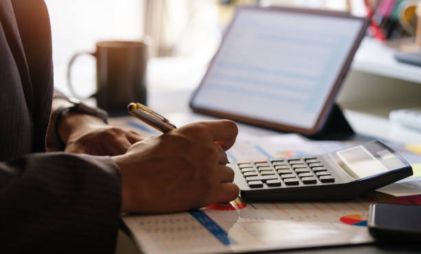 istock Millennial businessman working with digital tablet, using calculator to check the statistics and projections. 1514181034