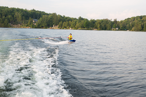 Female wakeboarder wakesurfing. Girl riding waterski cabel. Holding tow rope. Summer activities in the lake.