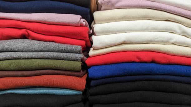 Different color fabrics stacked one on top of the other in a stack selling textiles in a store