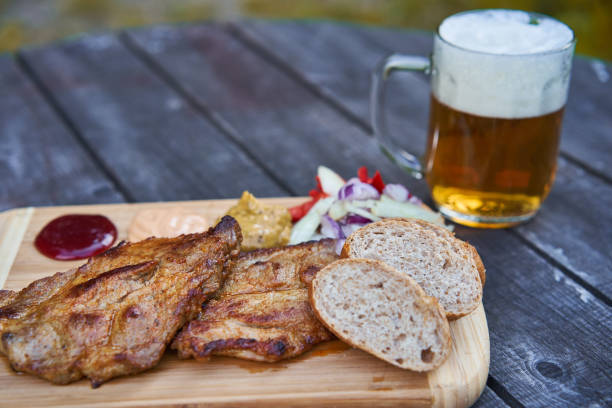 istock Wooden plate with two grilled pork steaks. 1514200128