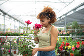 Woman in garden store chooses pots and pots for her roses, smelling flower