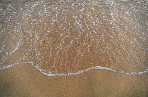 Sea water splashing sandy beach