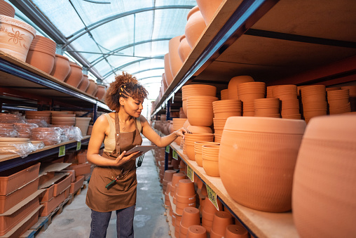 Woman in garden store chooses pots and pots for inventory with her tablet