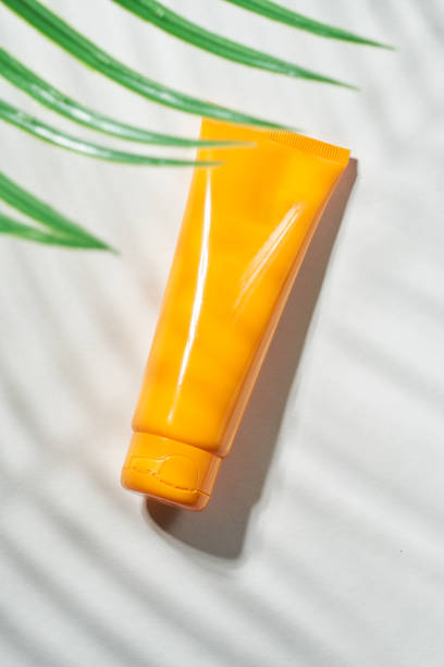 istock Summer sunscreen cream on sand background with shadow of palm leaf. 1514296660