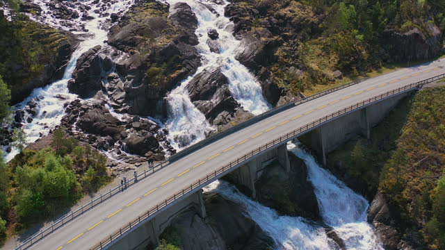 Aerial View of Cars Driving Idyllic Fjord Road Above Scenic Waterfall in Norway