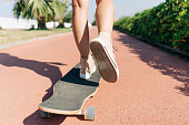 Close-up of female legs on a skateboard, one leg is repelled from the surface. Outdoor workout and hobby.
