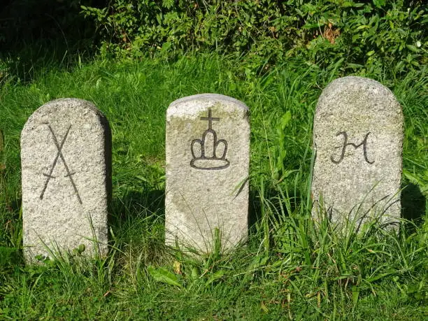 Old border marker stones with coat of arms on a meadow in Saxony, Germany