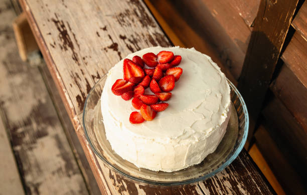 istock White cake decorated with strawberries on a wooden background. 1514318602