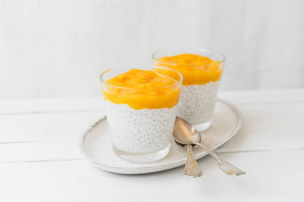 Dessert im Glas mit Quark, Chia Samen und Mango auf einem weißen Tablett