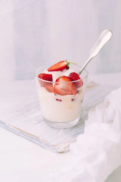 Dessert im Glas mit Quark und Erdbeeren auf einem Schneidebrett