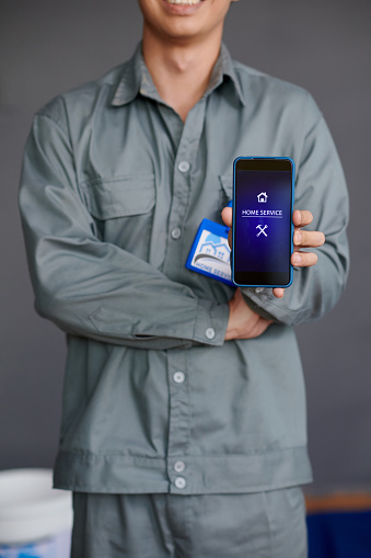 Cropped image of worker showing home service application on smartphone