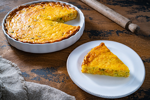 Vegetables quiche slice on plate homemade on wooden rustic table just baked