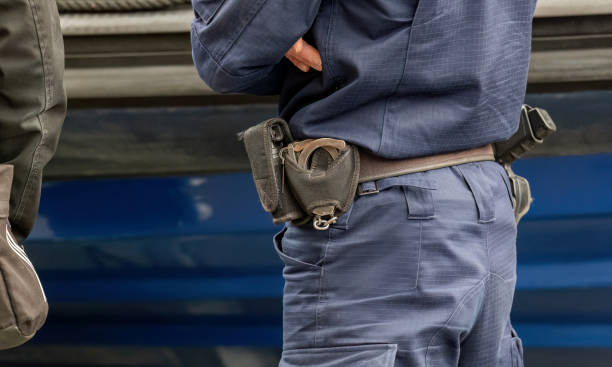 istock One single generic anonymous policeman, police officer wearing a blue uniform, equipment closeup, handcuffs, pepper spray, detail up close. Public security, emergency response service abstract concept 1514472467