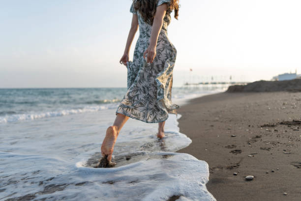 istock Woman walking barefoot on the beach. 1514486620